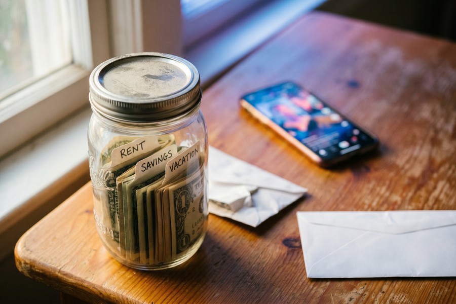 Person organizing labeled cash envelopes on a wooden desk, budgeting for the month