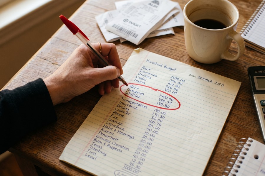 Single mom reviewing a bare-bones monthly budget spreadsheet at a kitchen table