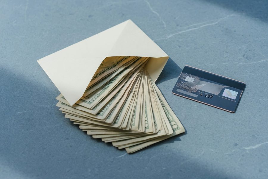 A smartphone screen displaying a digital envelope budget app next to a credit card