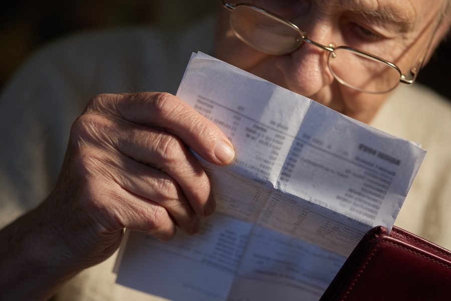 Elderly woman on phone looking concerned at kitchen table