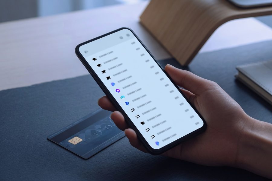 Person holding a smartphone displaying a list of subscription charges.