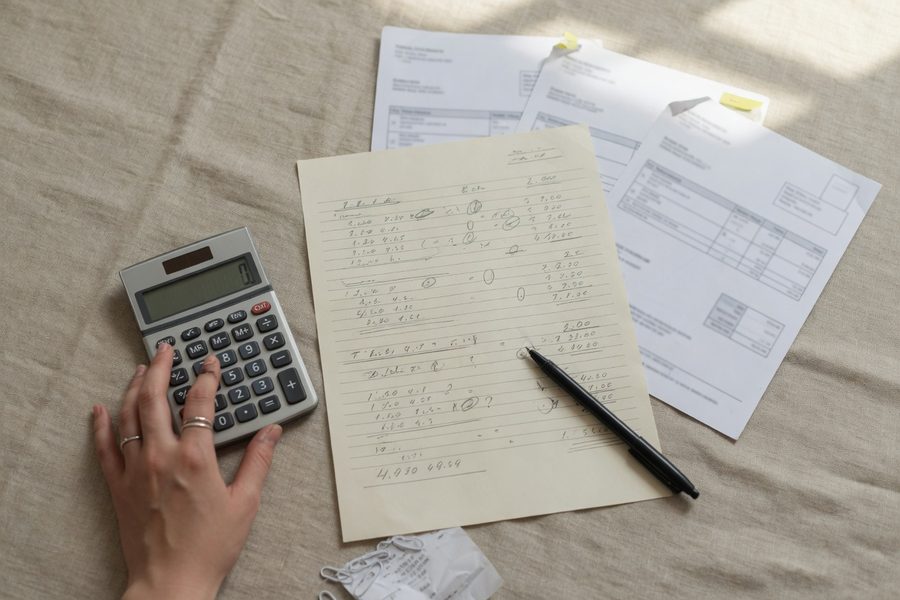 Freelancer comparing factoring fees against credit card interest on a laptop calculator