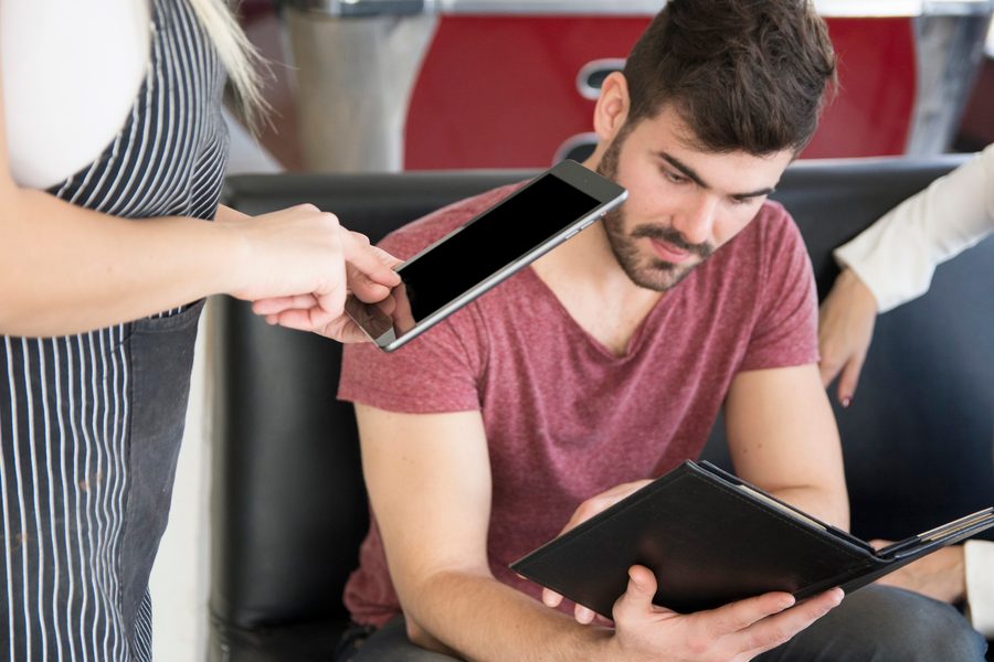 Hand drawing a subscription list beside a smartphone displaying a bank app
