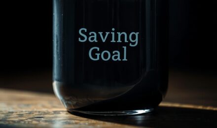 A person reviewing a savings plan on a laptop with a calendar and financial goals listed